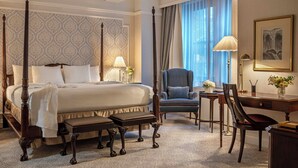 A four-poster bed with a canopy, a desk with a chair, and a large window with curtains. - Warwick New York (New York)