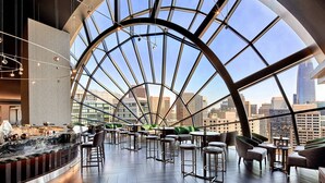 A modern interior with a large glass ceiling, a bar area, and seating arrangements.