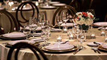 Una mesa de comedor dispuesta con platos, cubiertos, copas y velas, evocando una experiencia gastronómica elegante.