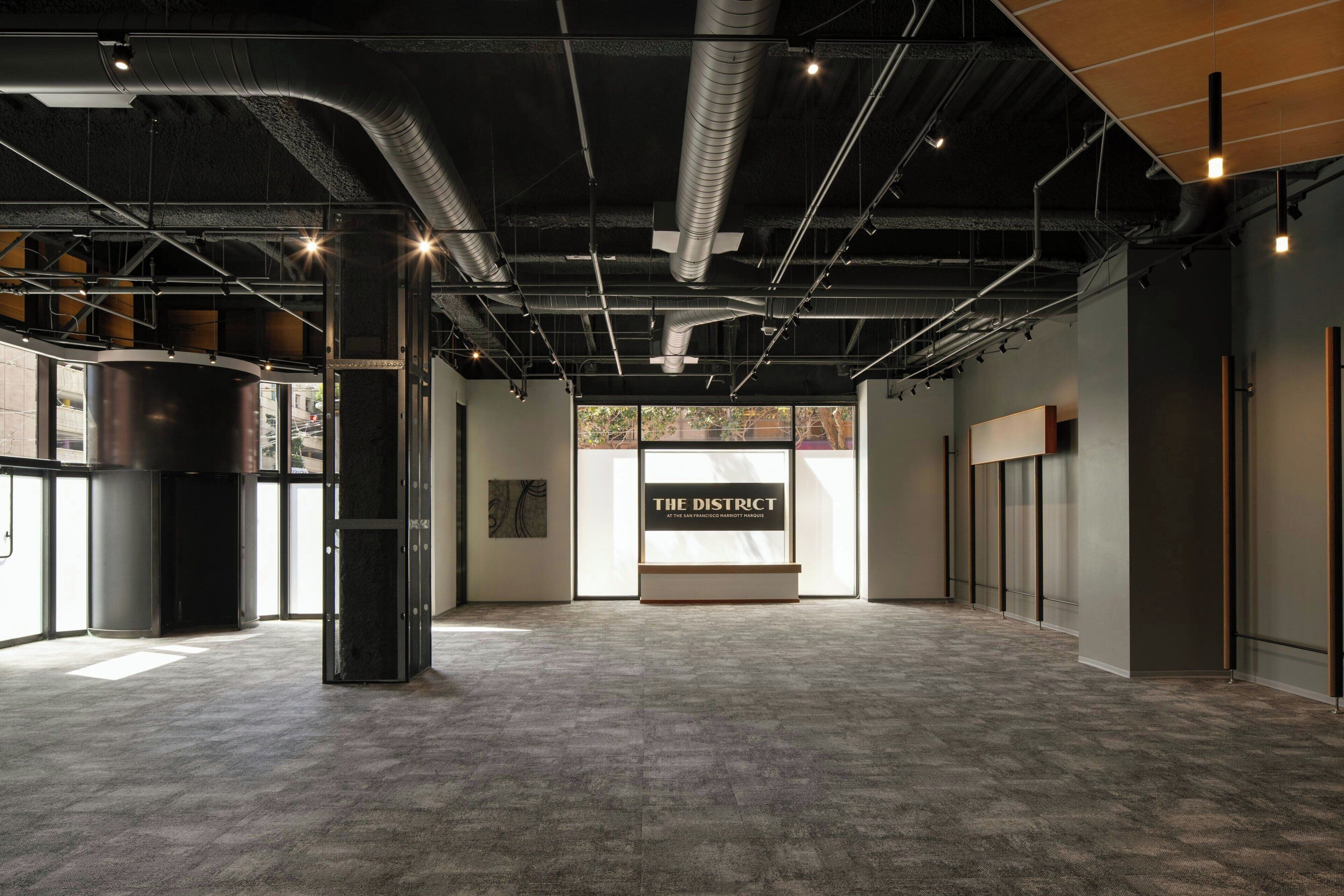 Un espace intérieur doté d’une vaste zone ouverte, de conduits apparents et d’une enseigne indiquant « THE DISTRICT ».