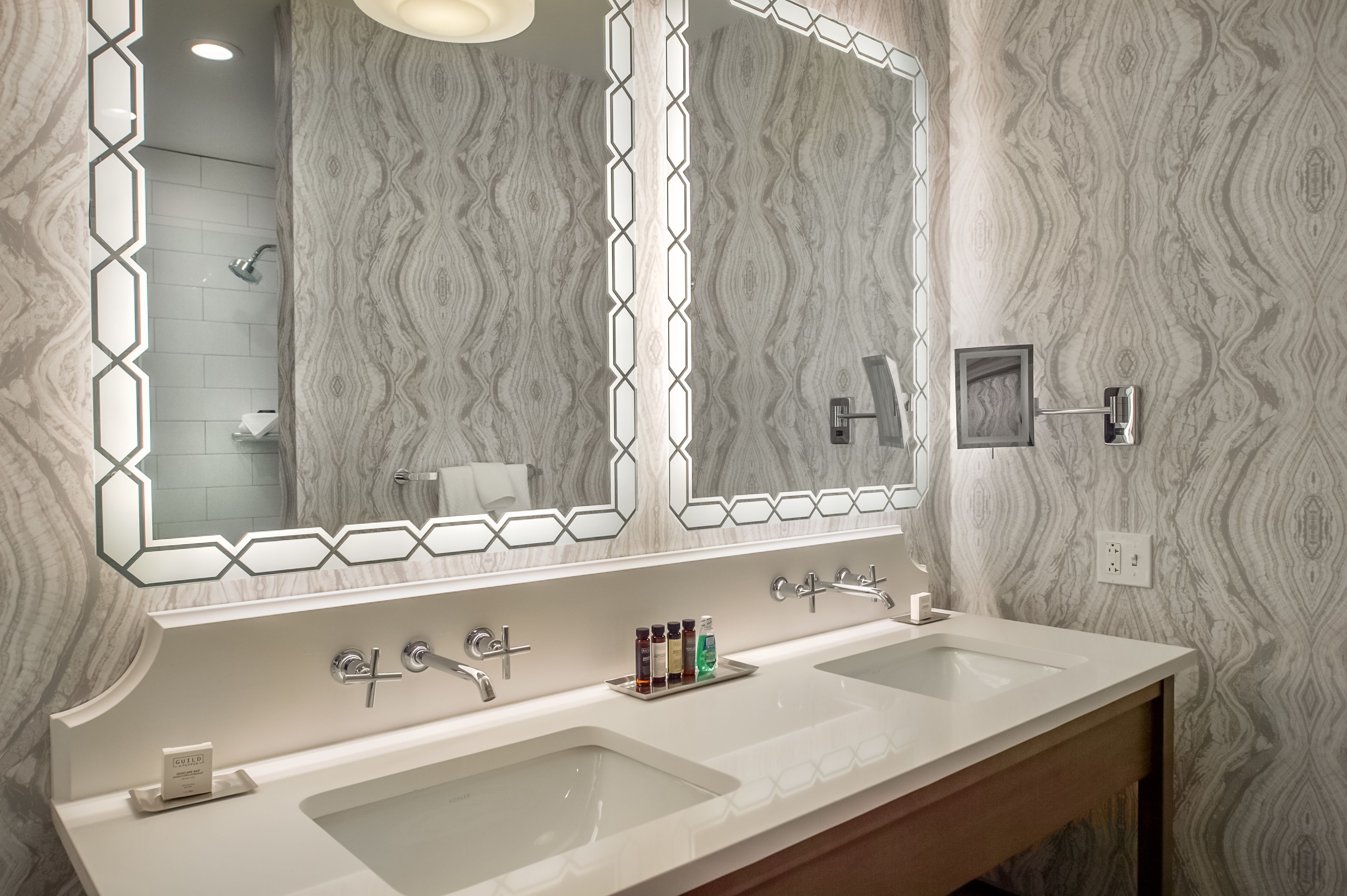 A bathroom with a large mirror, two sinks, and a vanity.