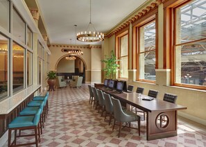 A spacious conference room with a long table, multiple chairs, and a large potted plant.