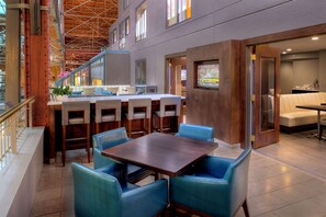 A modern dining area with a high ceiling, a central table, and blue chairs.