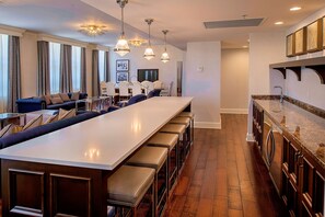 A modern kitchen with a long island counter, bar stools, and pendant lighting.