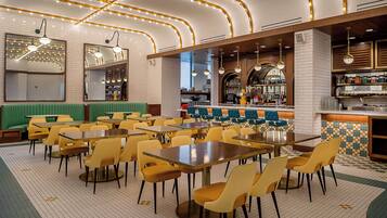 A restaurant with multiple tables and chairs, a bar area, and a seating section with green booths.