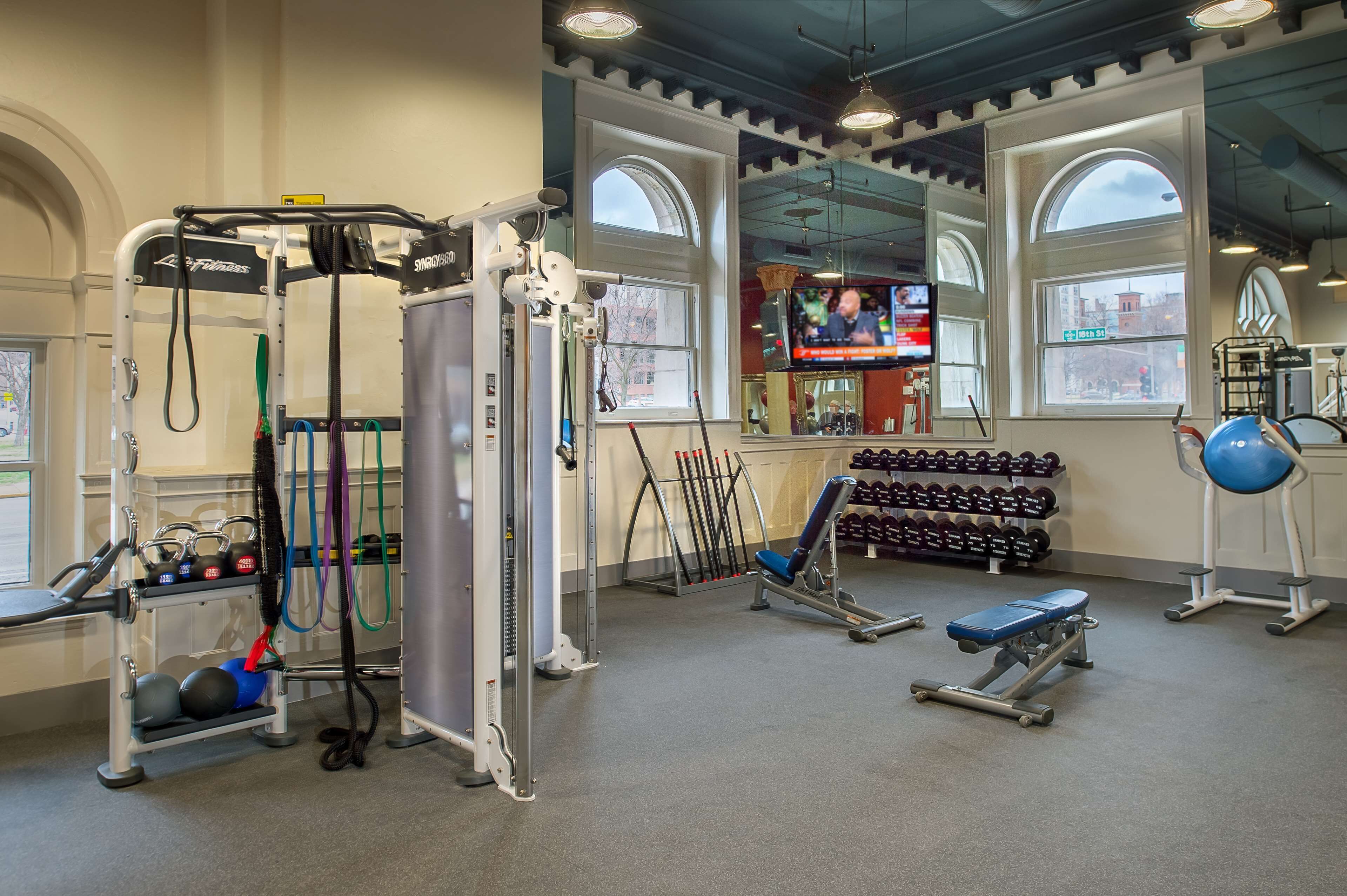 A gym with exercise equipment, dumbbells, and benches.