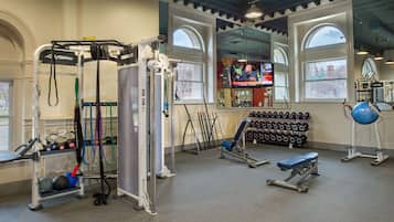A gym with exercise equipment, dumbbells, and benches.