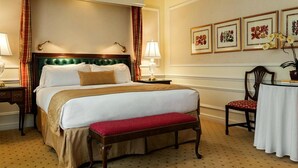 A hotel room with a large bed, a bench, a small table, and framed floral artwork on the wall. - The Orchards Hotel (Williamstown)