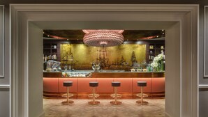 A bar area with a central counter, bar stools, and a decorative chandelier. - Plaza Hotel Lucchesi (Florence)