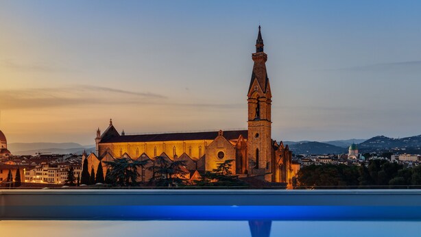 A historic church with a tall bell tower, surrounded by trees and a clear sky. - Plaza Hotel Lucchesi (Florence)