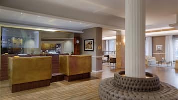 A spacious lobby with a reception desk, seating area, and a large column.