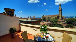 A balcony with a table set for breakfast, overlooking historic buildings and a clear blue sky. - Plaza Hotel Lucchesi (Florence)