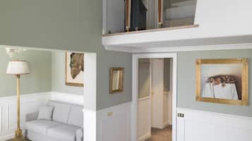 Un'ampia zona giorno con un divano, due poltrone, un tavolo rotondo e una scala che conduce a un piano superiore.