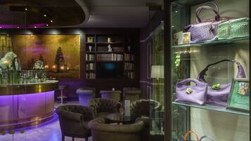 A bar area with a round bar, cushioned seating, and a glass display case with handbags.