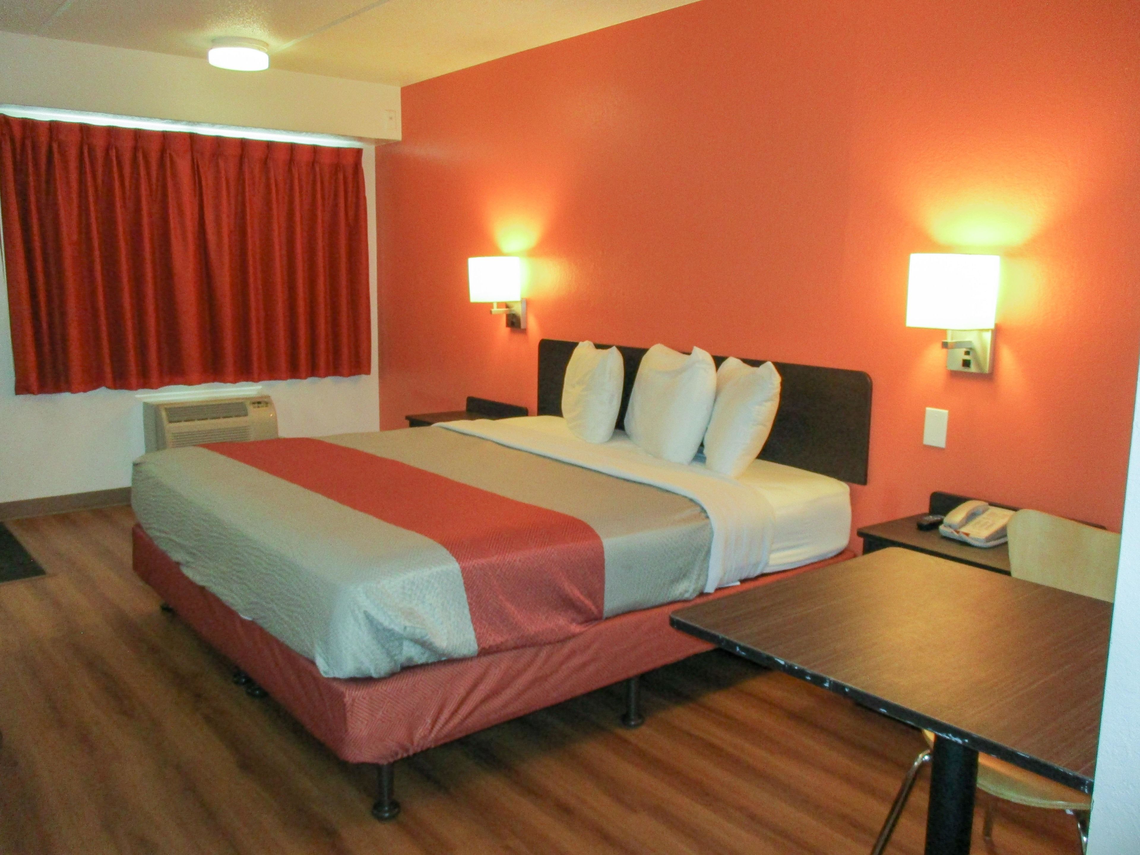 A hotel room with a bed, two bedside lamps, a desk, and a telephone.