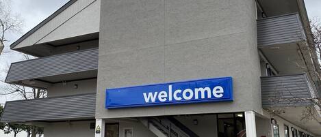 A modern building with a '6' sign and a 'welcome' sign, indicating a hotel.