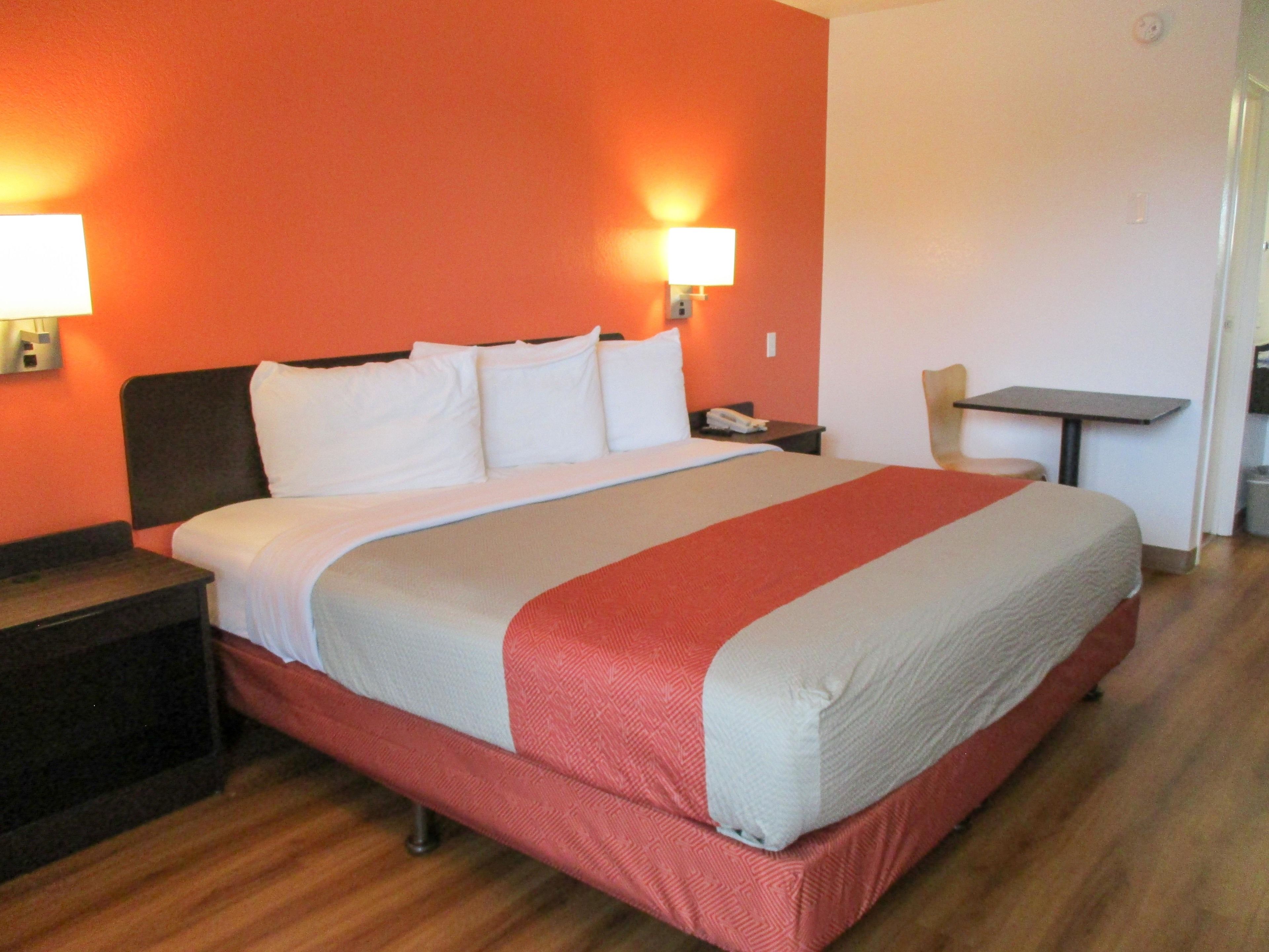 A hotel room with a bed, nightstands, a desk, and a chair.