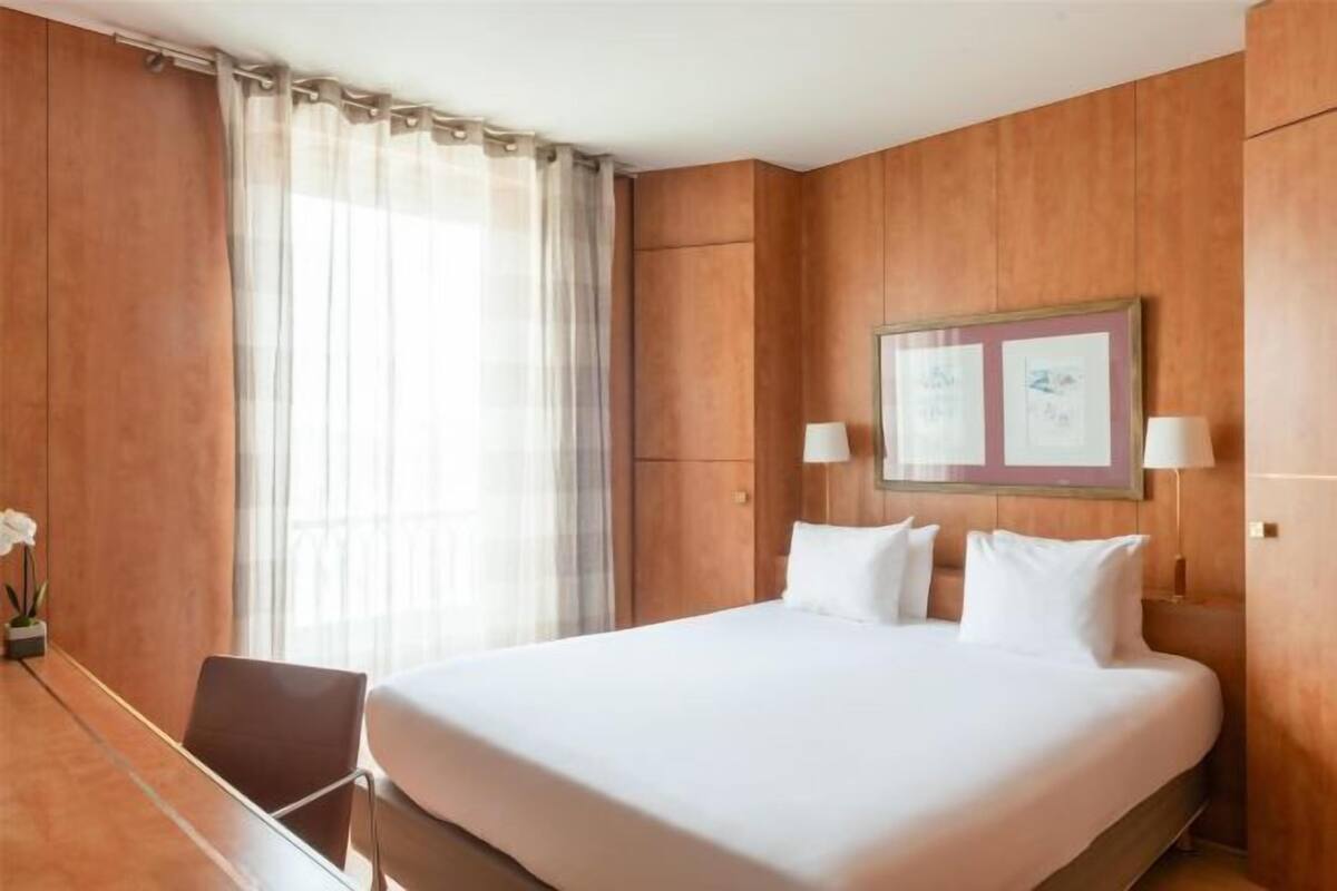 A hotel room with a large bed, a desk, and a chair.