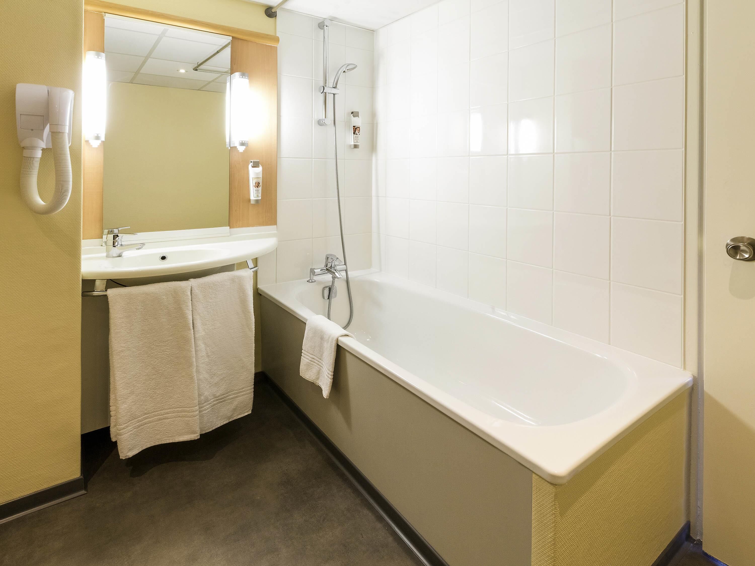 A bathroom with a bathtub, a sink, and a mirror.