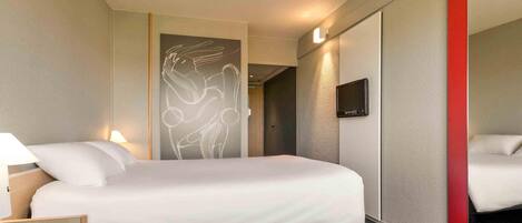 Una habitación de hotel con cama, lámparas de noche, televisión y un espejo grande.