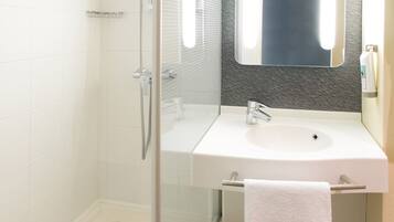 A modern bathroom with a glass-enclosed shower, a white sink, and a large mirror above the vanity.