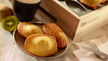 Une assiette de pâtisseries, une tasse de café et une boîte en bois étiquetée « cuisine ibis ».