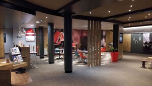 Un interior moderno con una mesa de recepción, una zona de estar y un gran letrero rojo.