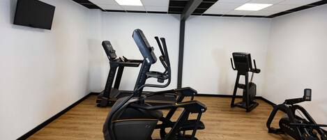 Uma academia com esteiras, elíptico e bicicleta ergométrica.