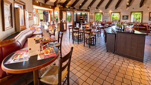 Un restaurante con cabinas, mesas y una zona de bar.