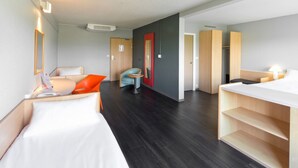 Una habitación de hotel con una cama, un escritorio, una silla, un espejo y un armario.