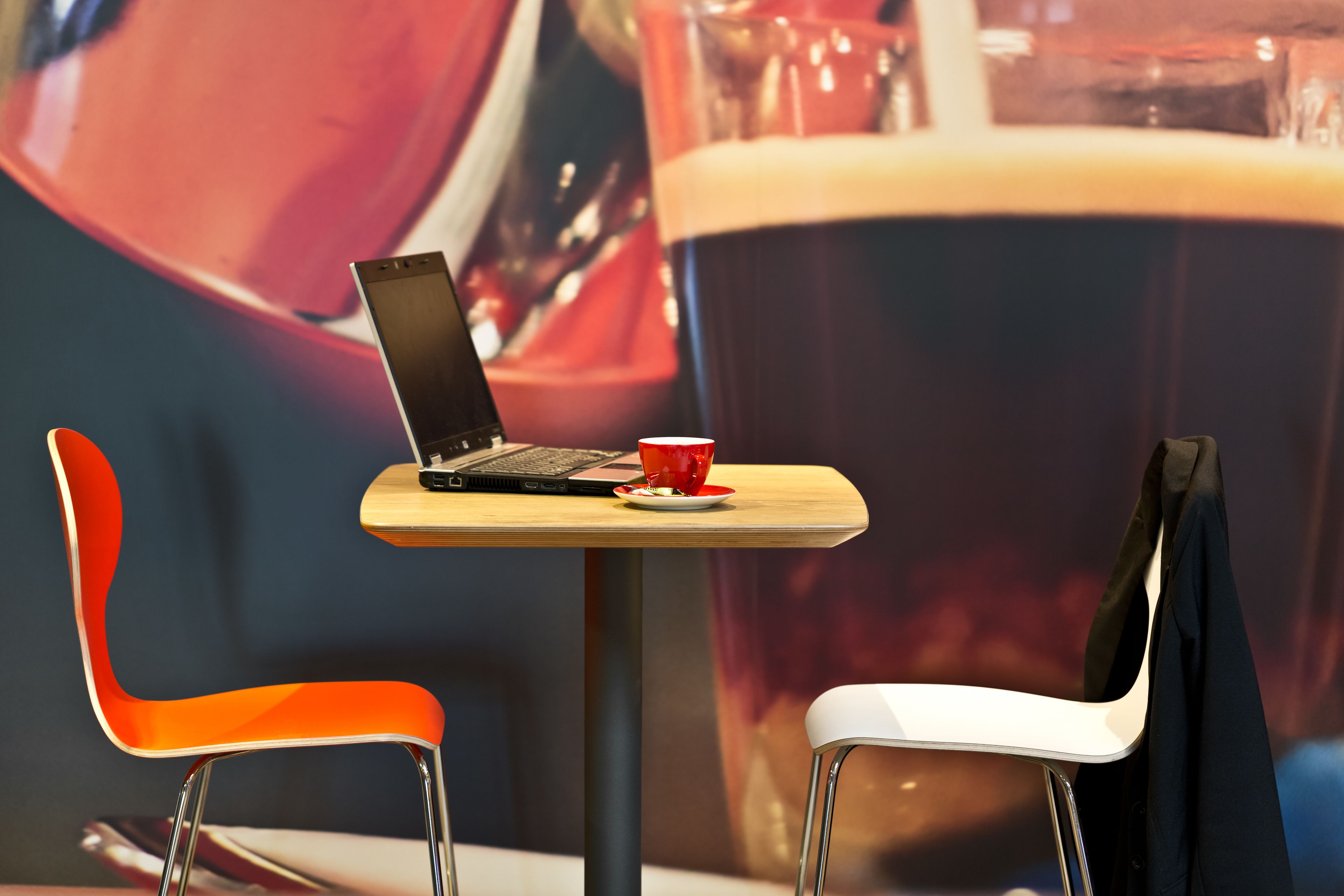 Una mesa con una laptop, un vaso rojo y una jarra de cerveza.