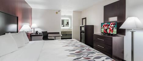 A hotel room with a large bed, a desk, a TV, and a dresser.
