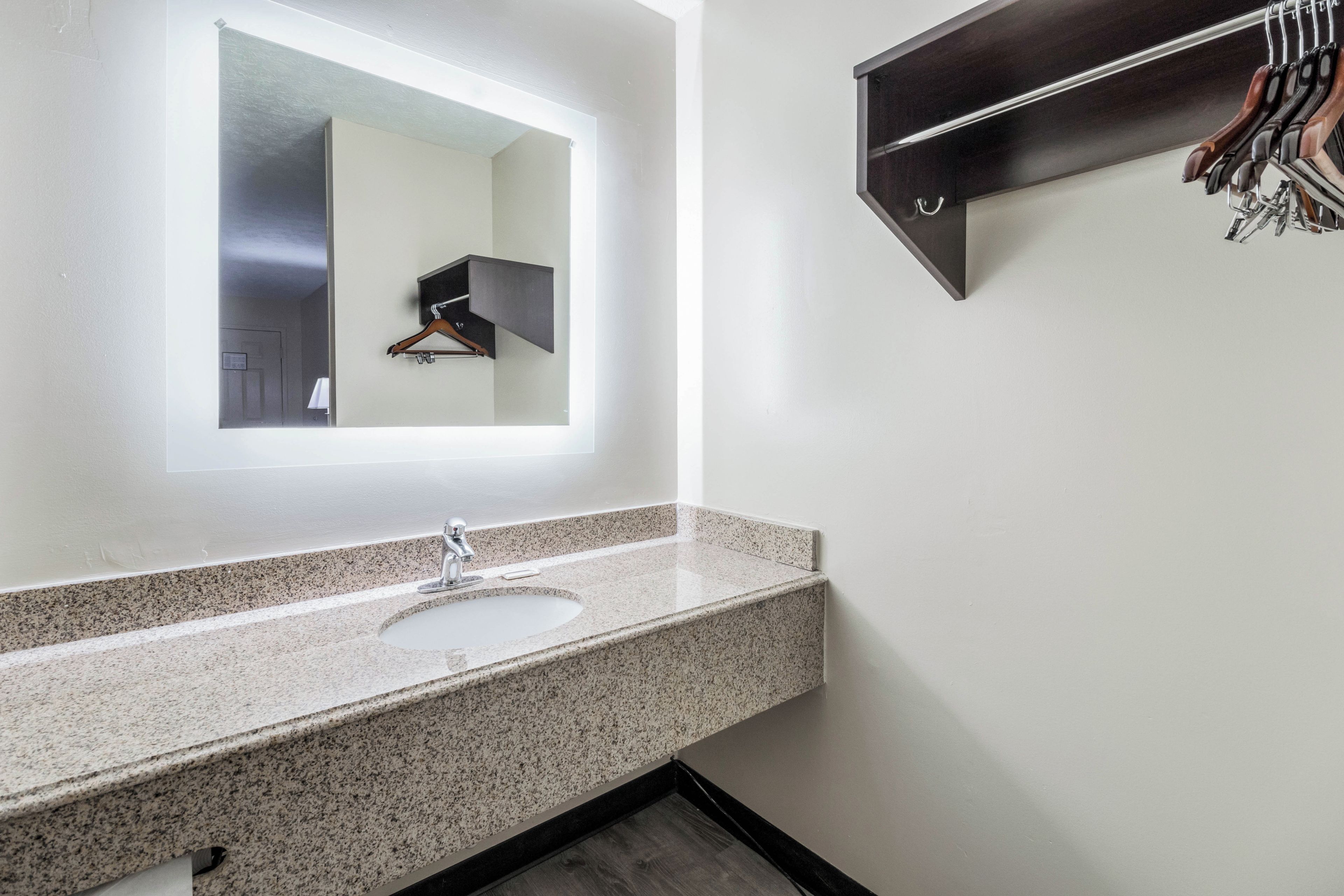 A bathroom with a granite countertop sink, a mirror, and a wall-mounted towel rack.