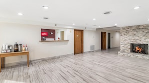 A spacious hotel lobby with a marble floor, a reception desk, a free Wi-Fi sign, a clock, and a fireplace. - Red Roof Inn Cadiz (Cadiz)
