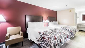A hotel room with a bed, a chair, a nightstand, and a lamp.