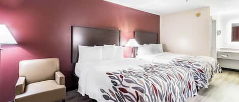 Una habitación de hotel con una cama, una silla, una mesita de noche y una lámpara.