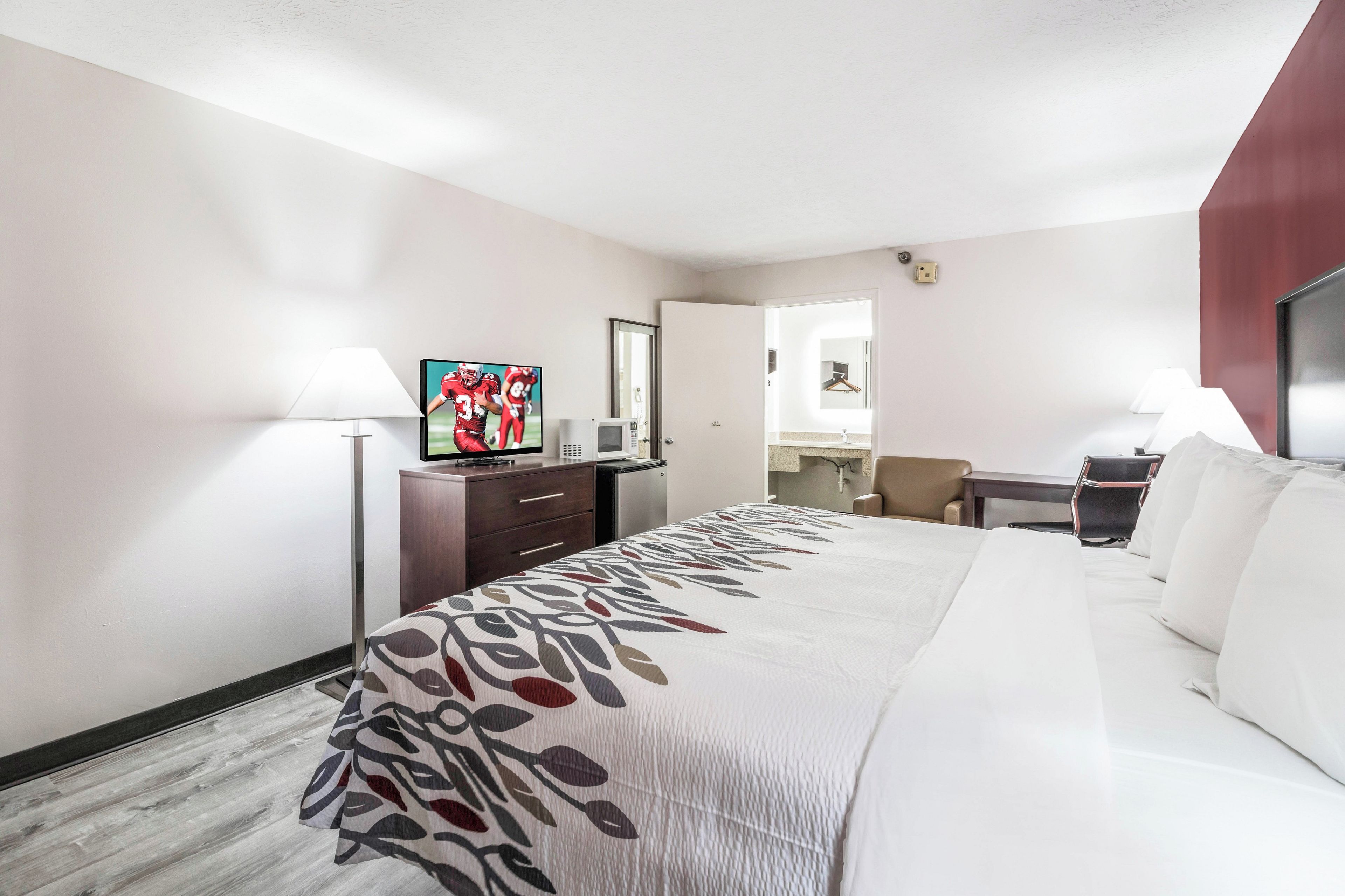 Une chambre d’hôtel équipée d’un lit, d’un bureau, d’une chaise, d’une télévision et d’un miroir.