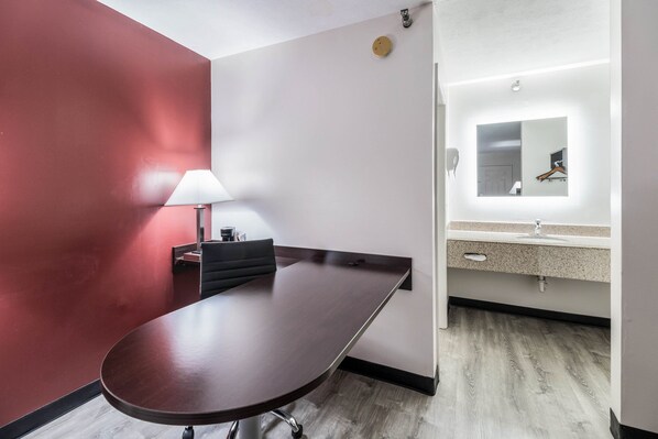 A conference room with a dark wooden table, a black chair, and a white lamp. - Red Roof Inn Cadiz (Cadiz)