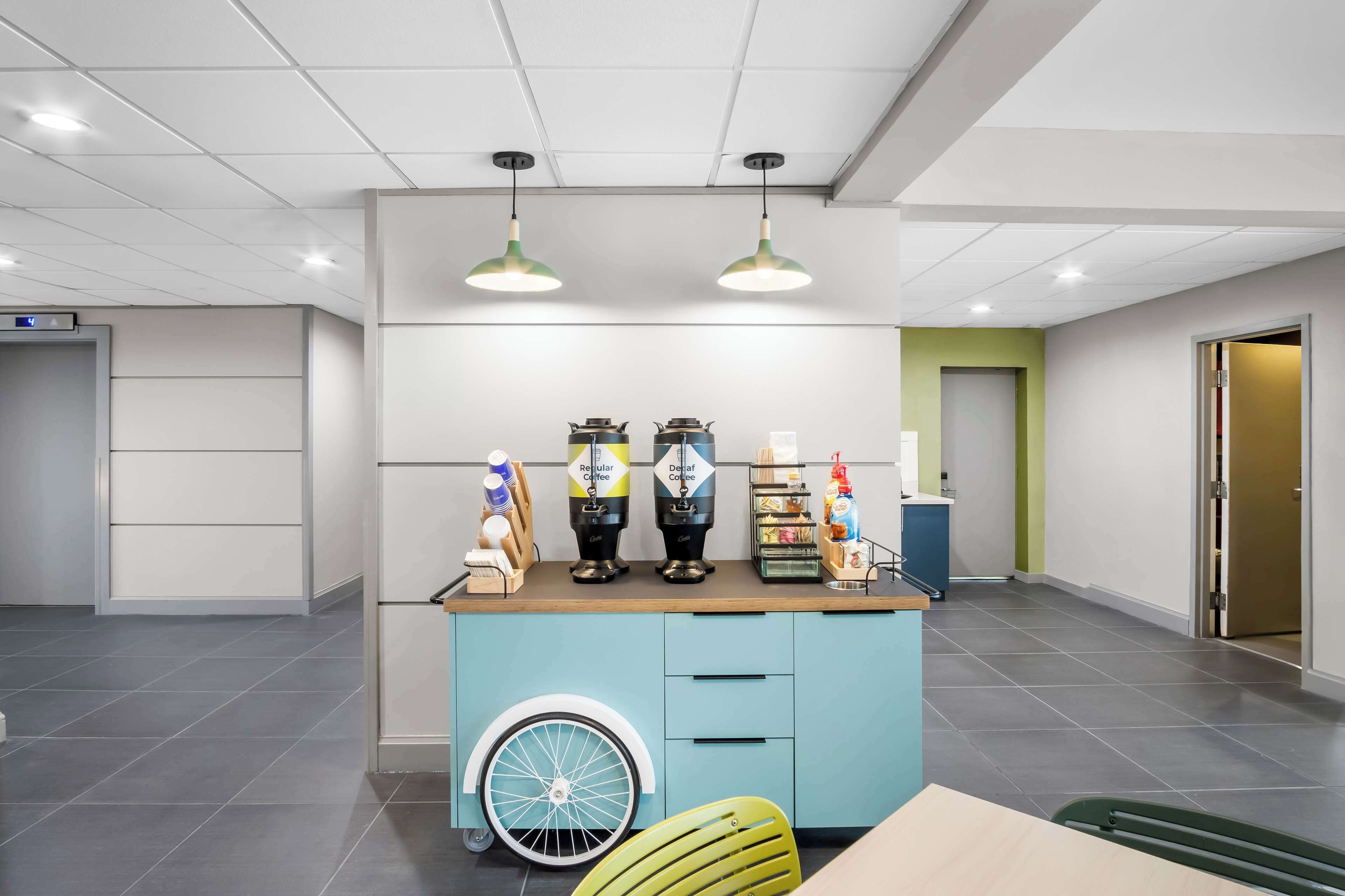 A modern interior with a blue counter, two coffee machines, and a wheelchair-accessible wheelbarrow.