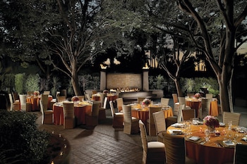 A circular outdoor seating area with a fire feature, surrounded by a low brick wall and trees. at Warner Center Marriott Woodland Hills