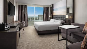 Habitación de hotel con una cama grande, un escritorio, televisión y vistas de la ciudad.