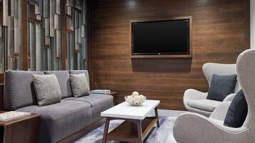 A modern living room with a grey sofa, a white coffee table, and a grey armchair.