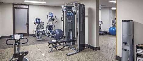 A gym with various exercise equipment including a treadmill, elliptical, and weight machines.