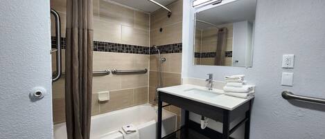 A modern bathroom with a bathtub, shower, and sink.