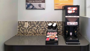 A coffee station with a coffee machine, a cup of coffee, and a sign advertising complimentary coffee. - Motel 6 Baytown, TX - Garth Rd (Baytown)
