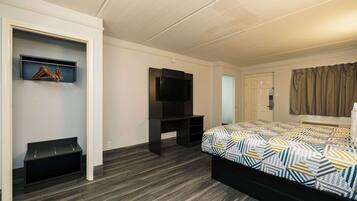 A bedroom with a bed, a TV, a coat rack, and a wardrobe.