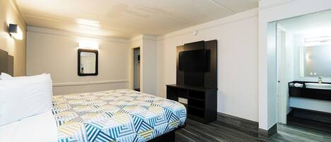 Une chambre d’hôtel avec un lit, une télévision, un miroir et une salle de bain.