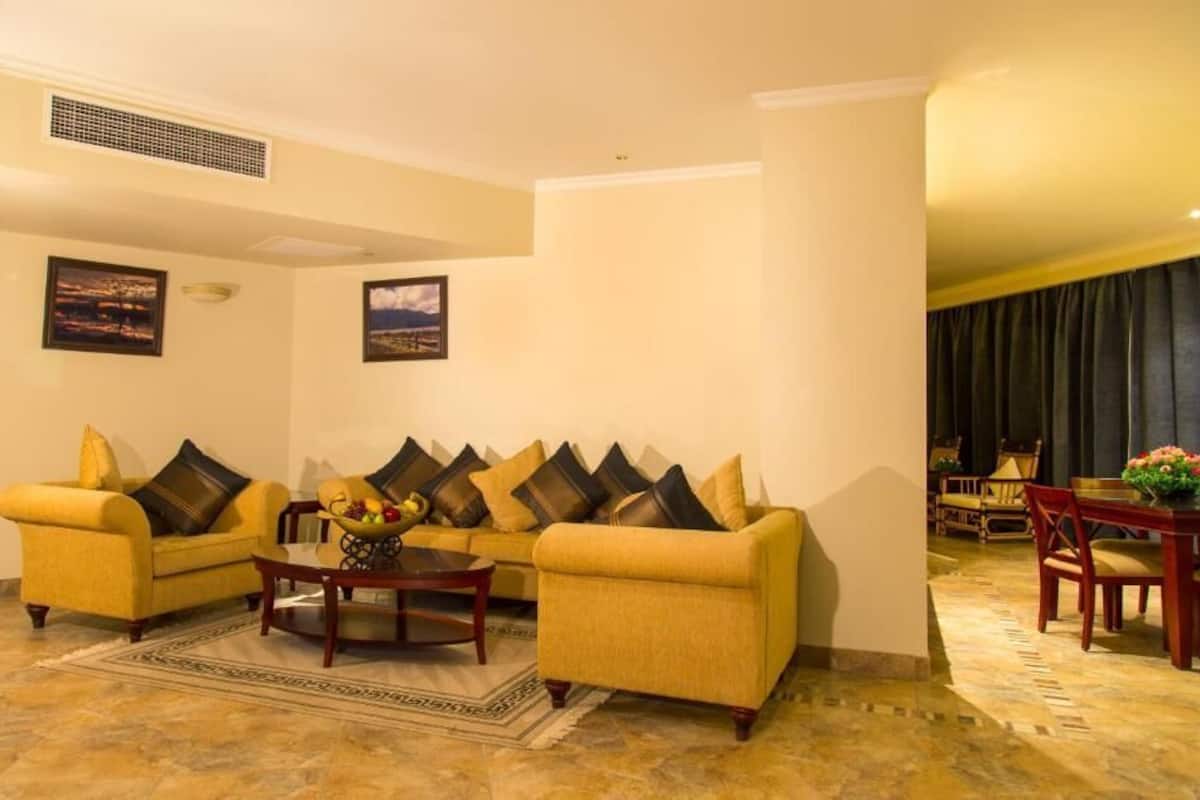 A living room with two yellow sofas, a coffee table, and a dining area with a table and chairs.