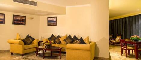 A living room with two yellow sofas, a coffee table, and a dining area with a table and chairs.