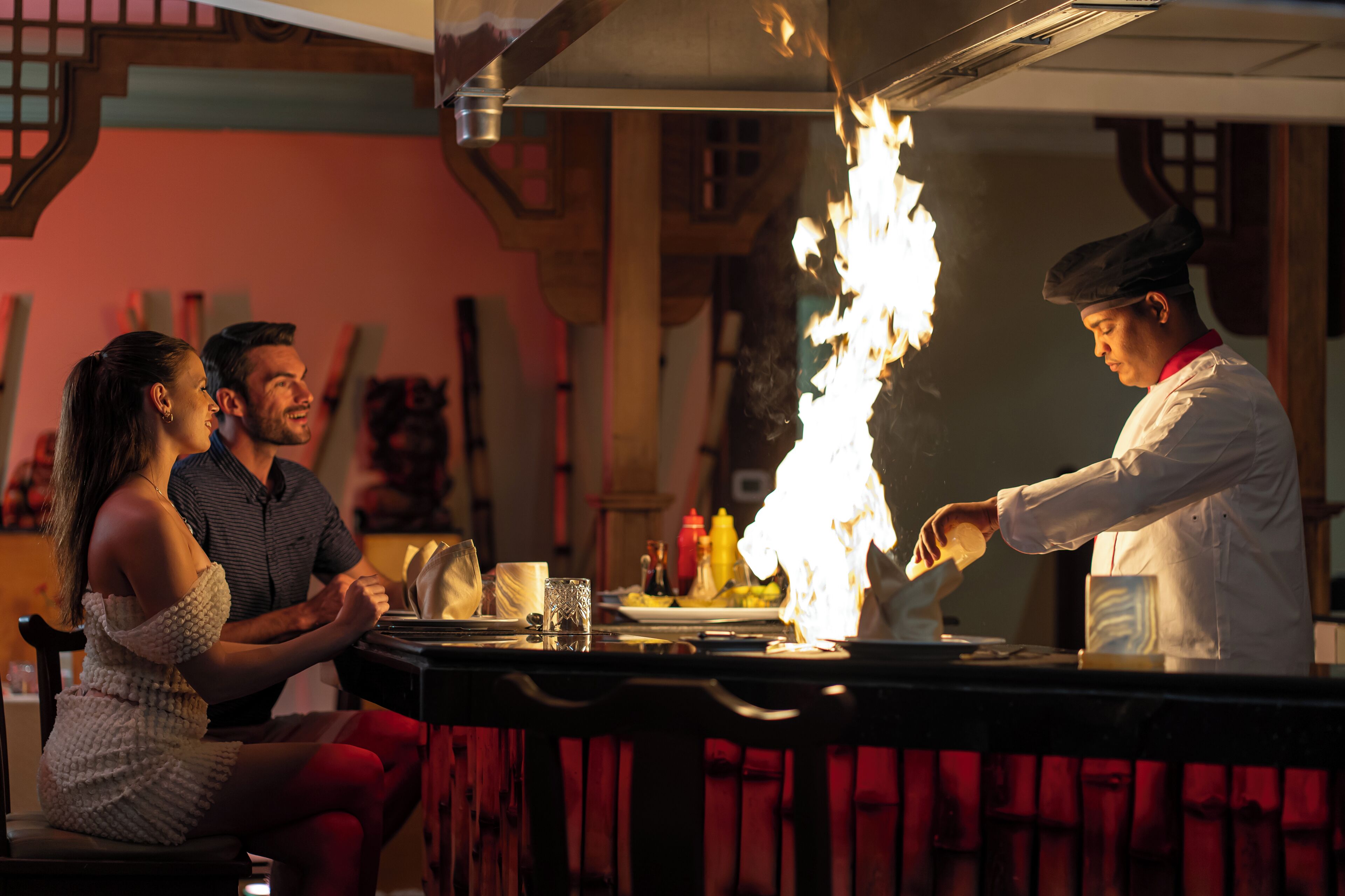 A chef performing a flambé with a fire in a kitchen setting.
